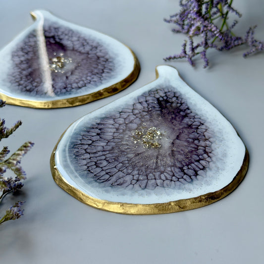 Decorative coasters with a gold edge and purple center on a light surface with lavender flowers.