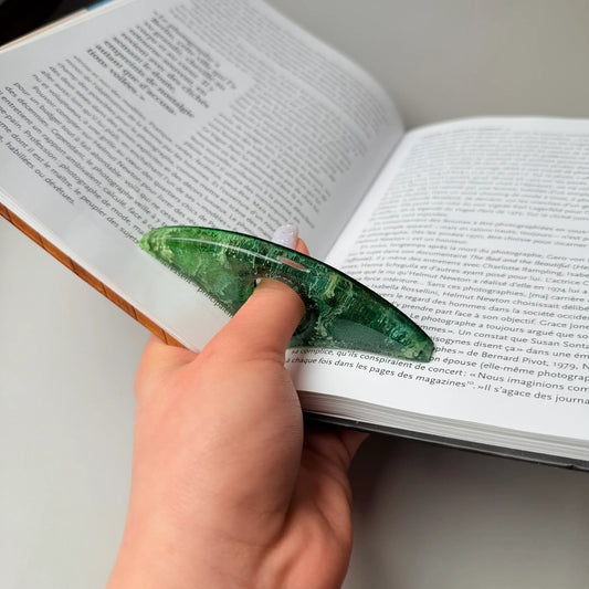 Reader holding curved green epoxy resin page holder with petri design during reading.