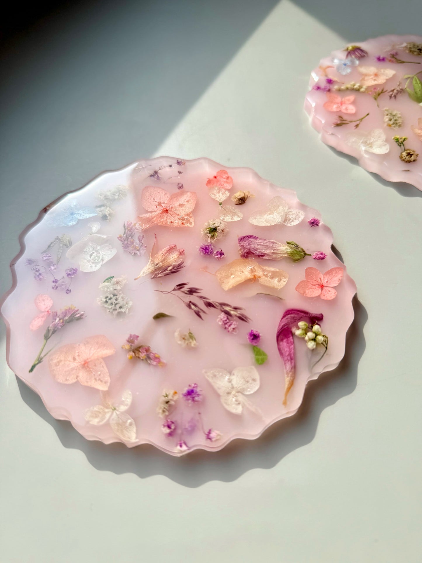 Handmade resin coaster with floral and butterfly designs on a light background