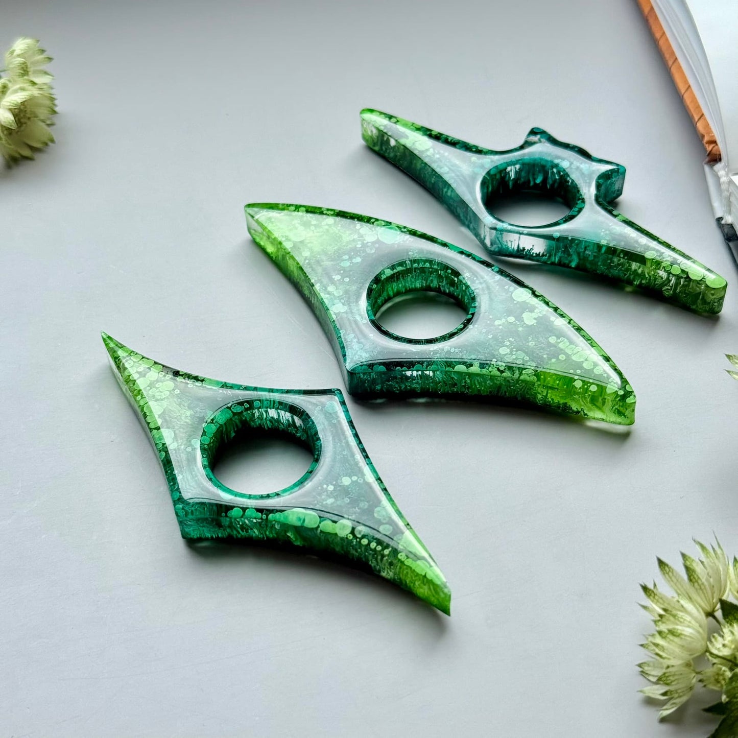 Three green alcohol ink resin page holders arranged diagonally, showing glossy finish and artistic texture.