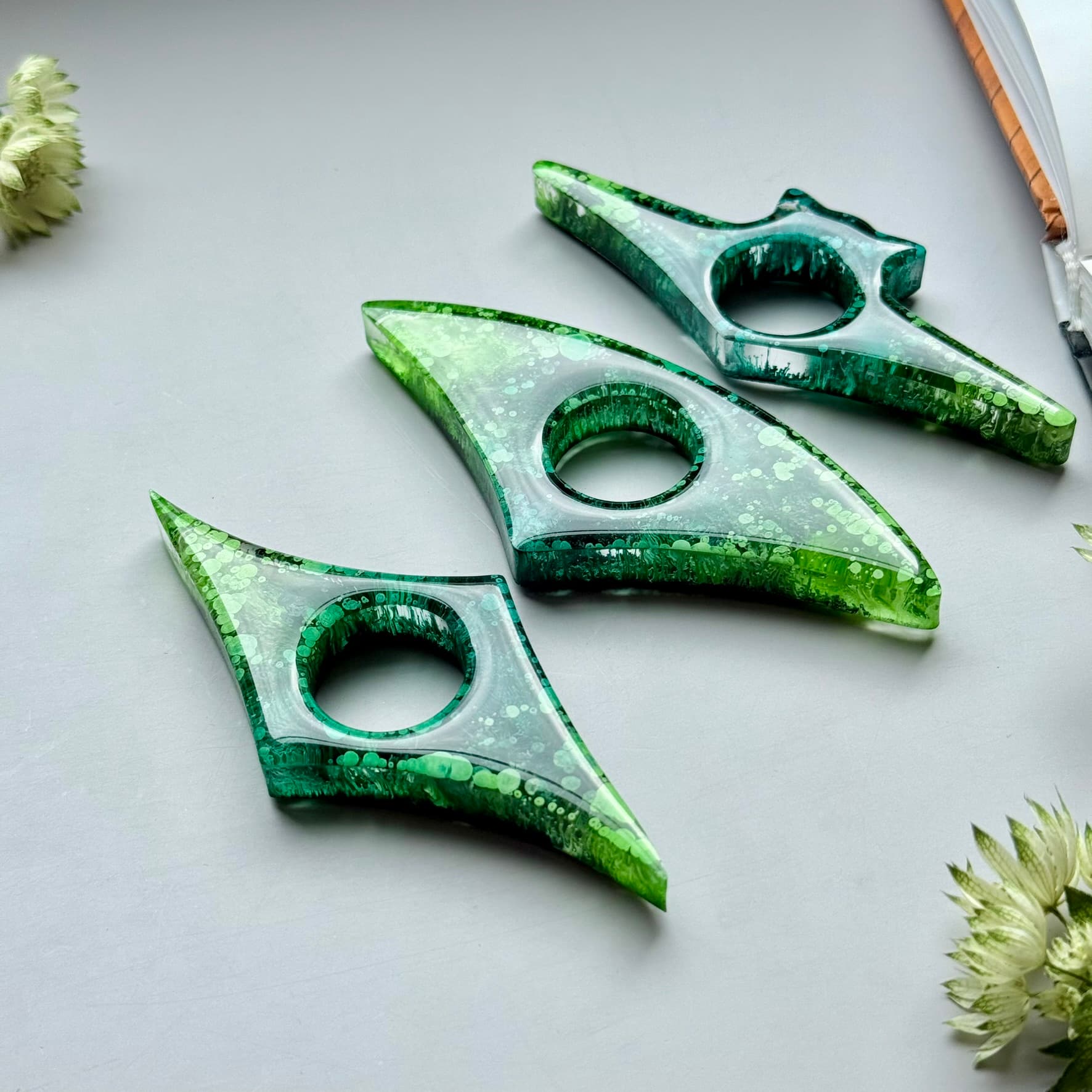 Three green alcohol ink resin page holders arranged diagonally, showing glossy finish and artistic texture.