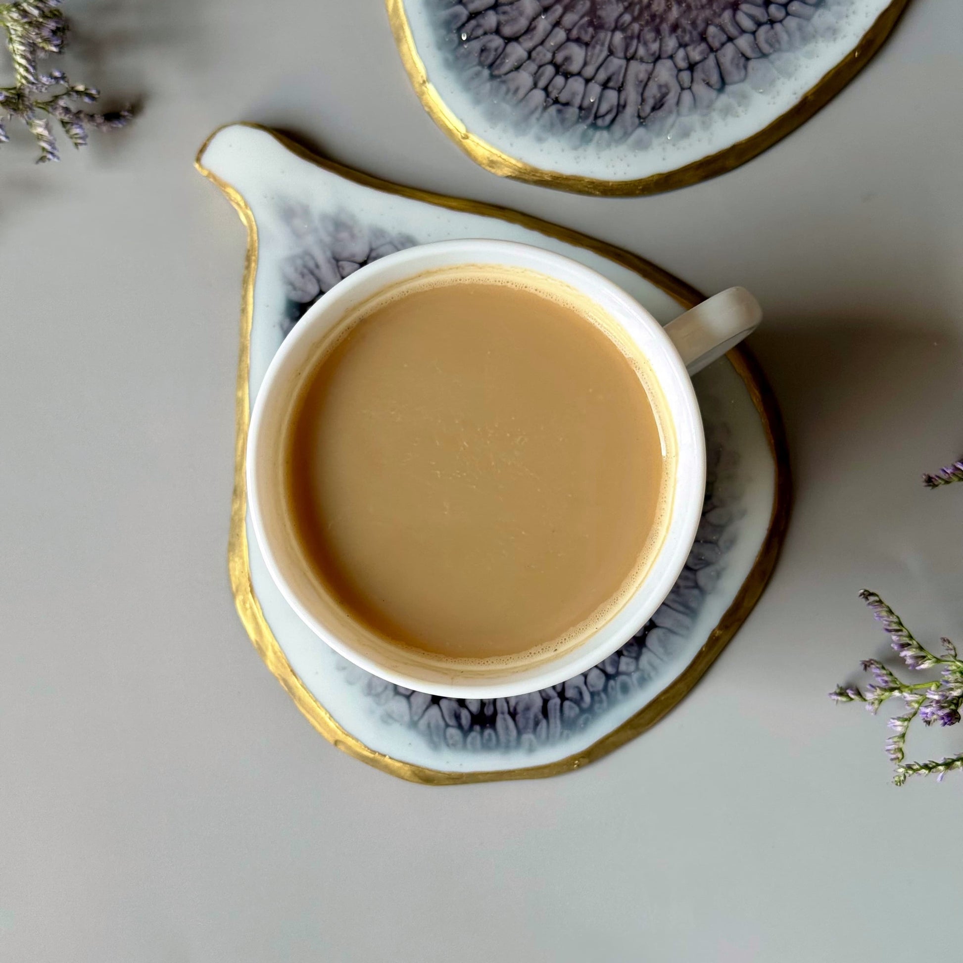 Cup of coffee on a decorative saucer with a textured coaster in the background