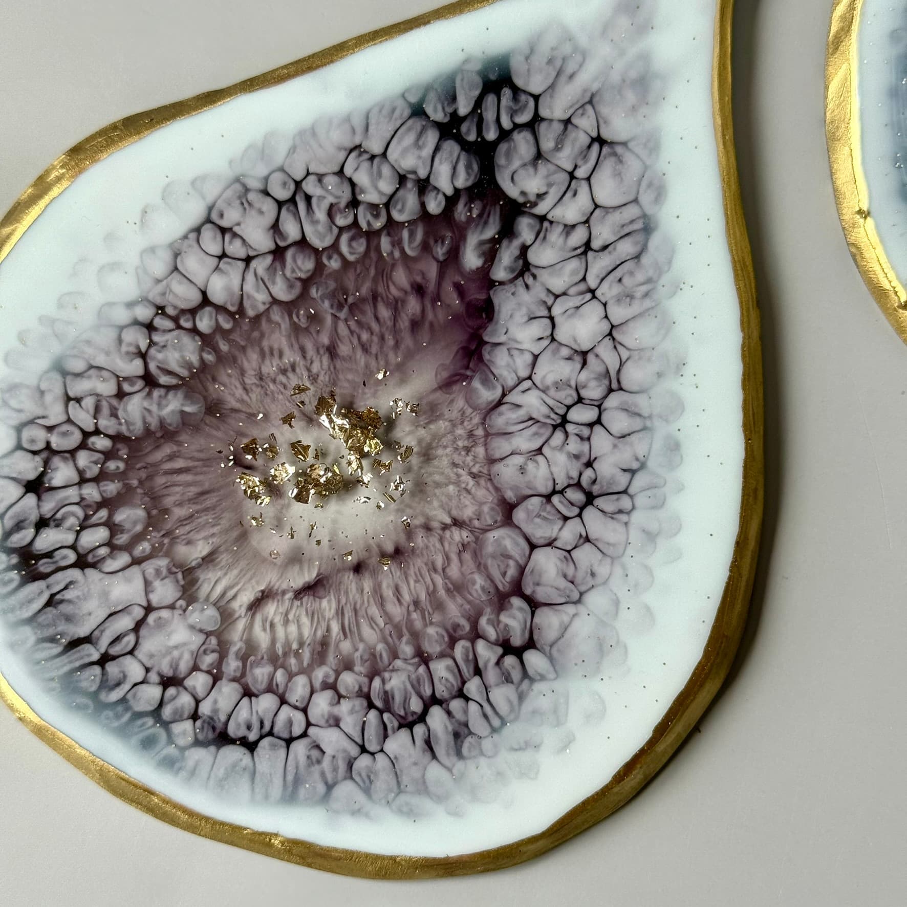 Close-up of a decorative coaster with a textured surface and gold edge on a light background