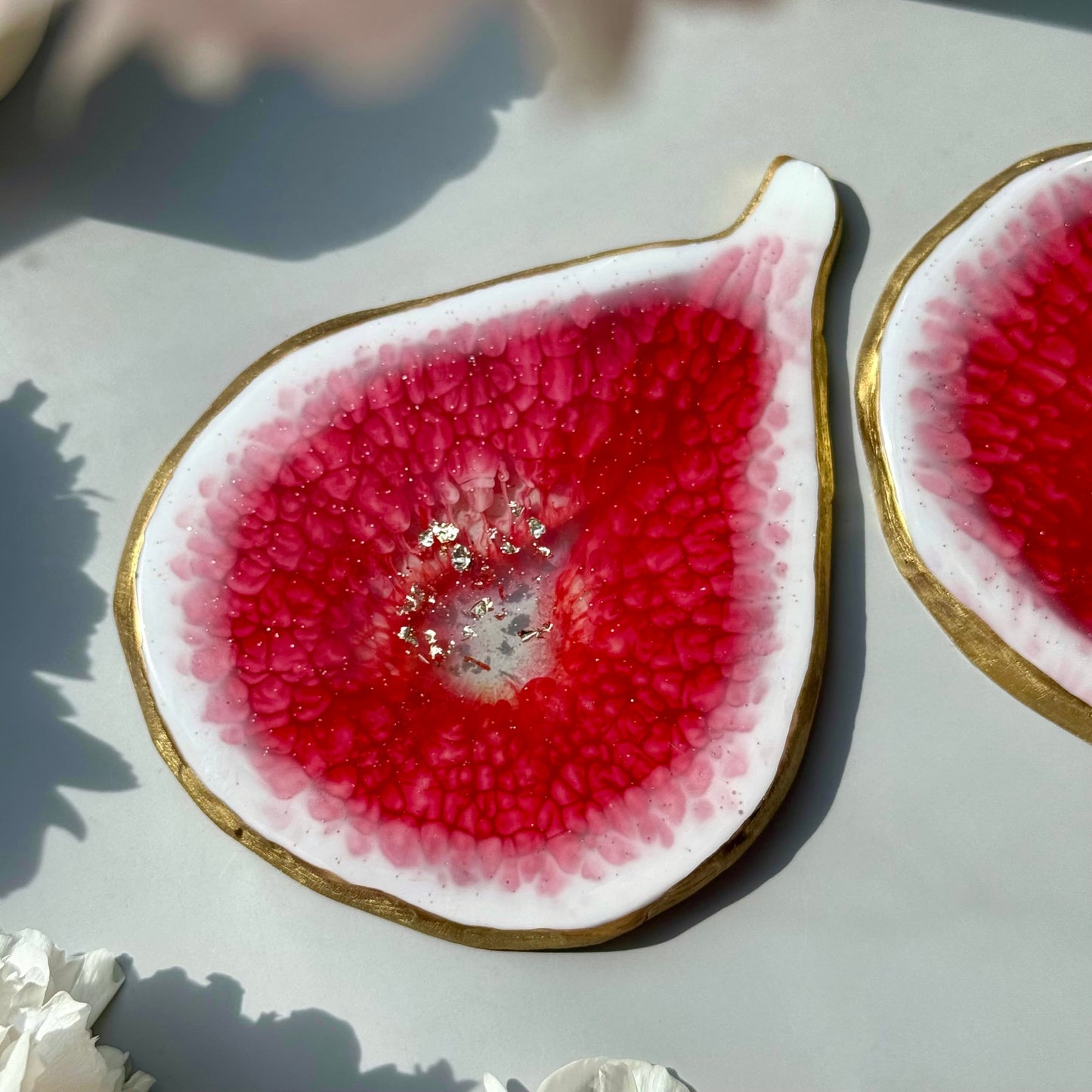 Close-up of a fig-shaped handmade coasters with pink interior on a light surface