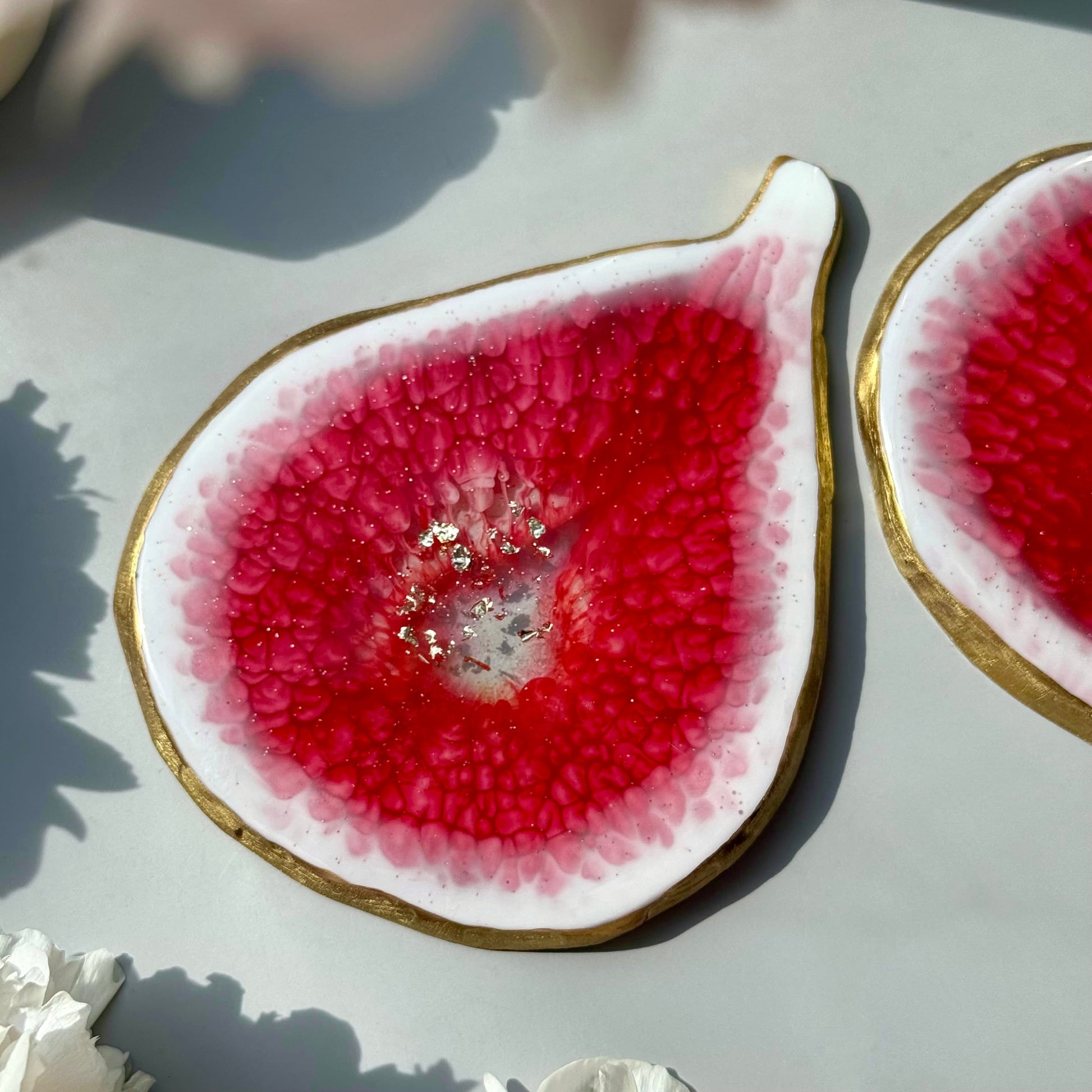 Close-up of a fig-shaped handmade coasters with pink interior on a light surface