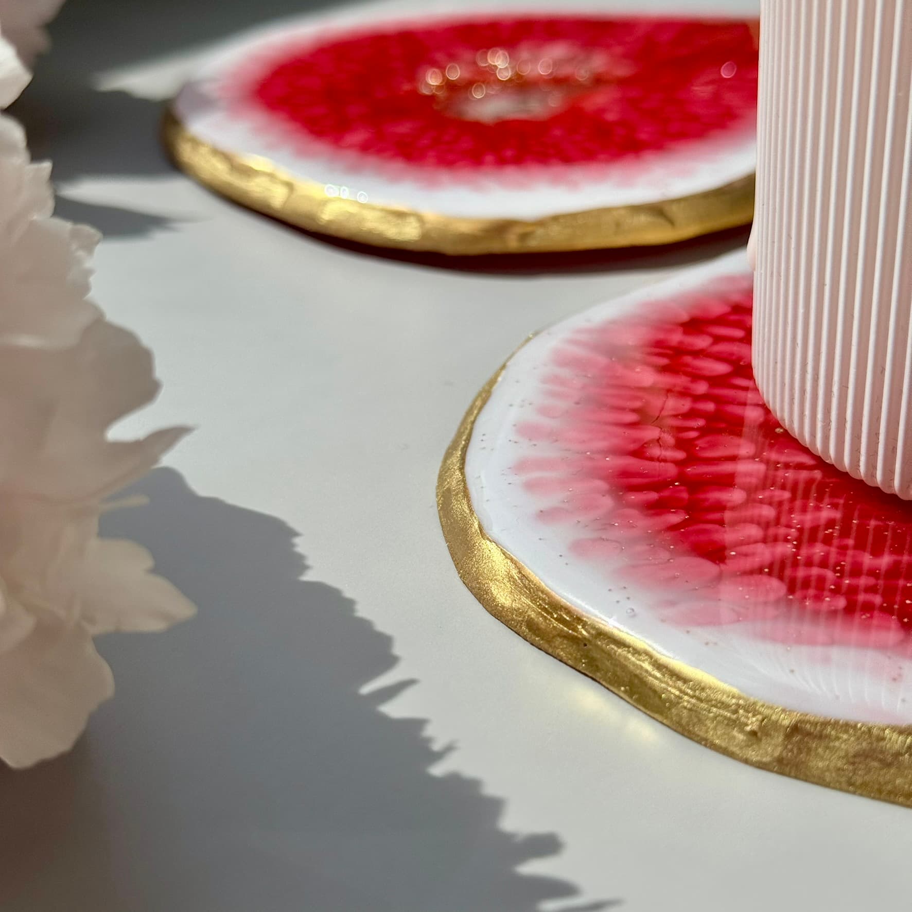 Close-up of handmade fig-shaped coasters with gold rims on a light surface.