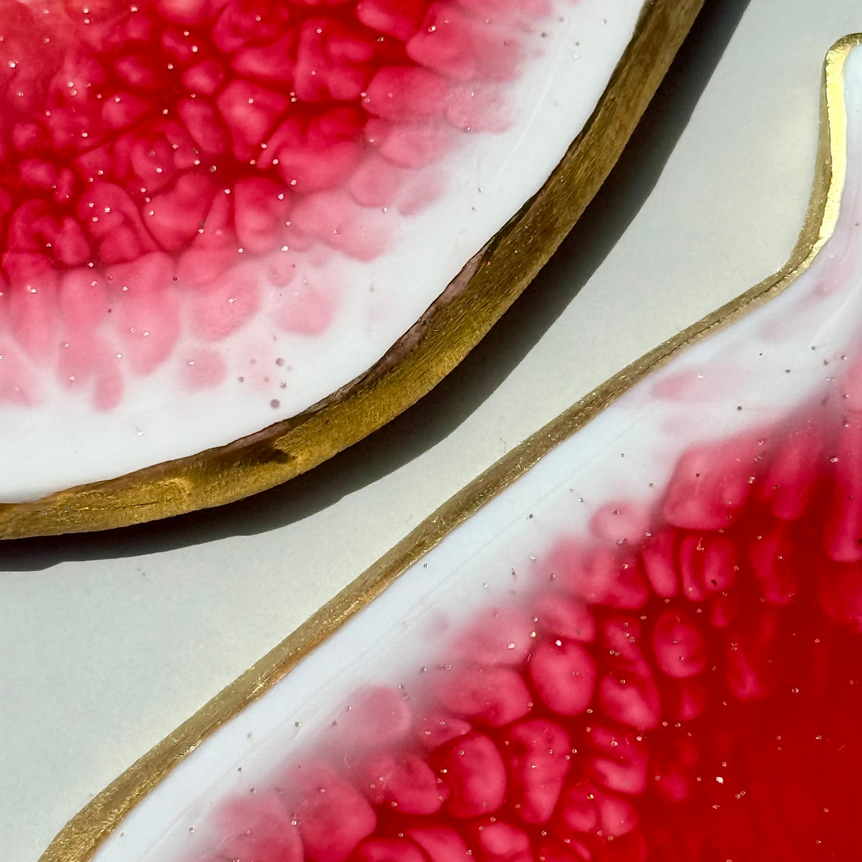 Close-up of a fig-shaped handmade coaster with pink flesh and brown skin on a light background.