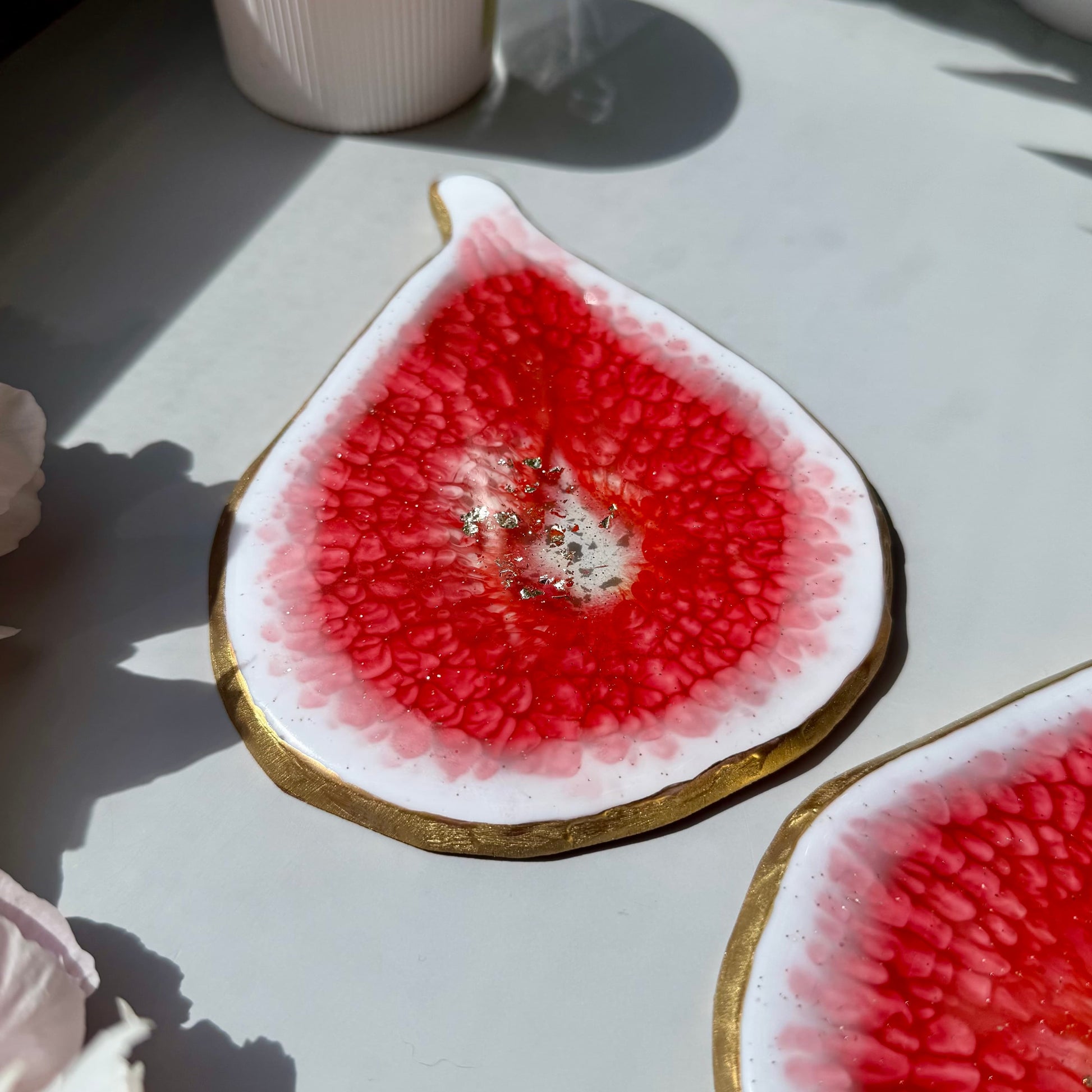 Handmade fig-shaped coasters with a gold rim on a light surface