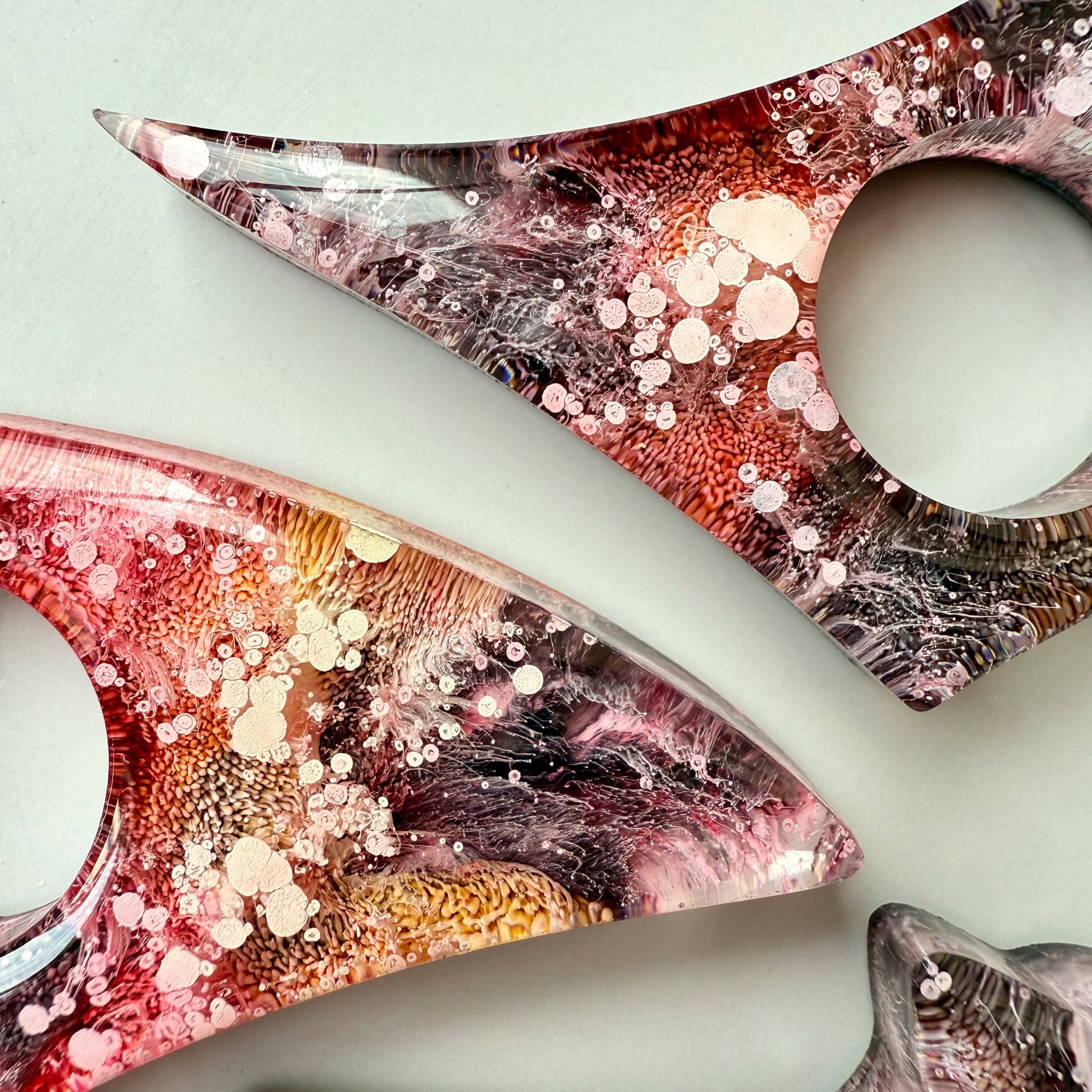 Close-up of handmade alcohol ink resin page holders with vibrant pink, gold, and black petri textures, showcasing intricate detail.