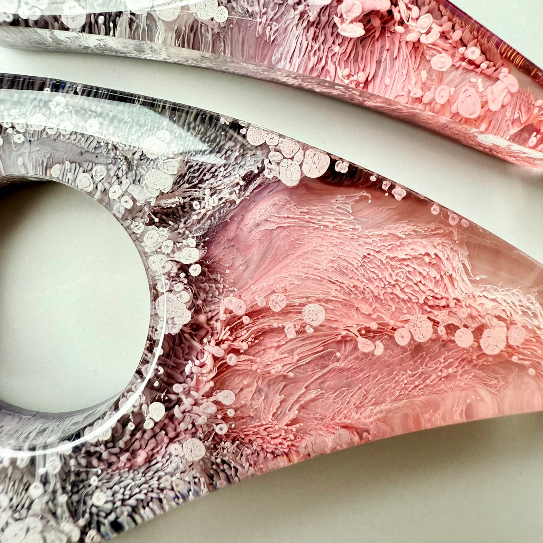 Close-up of pink and smoky gray handmade resin page holder showing detailed petri ink textures.