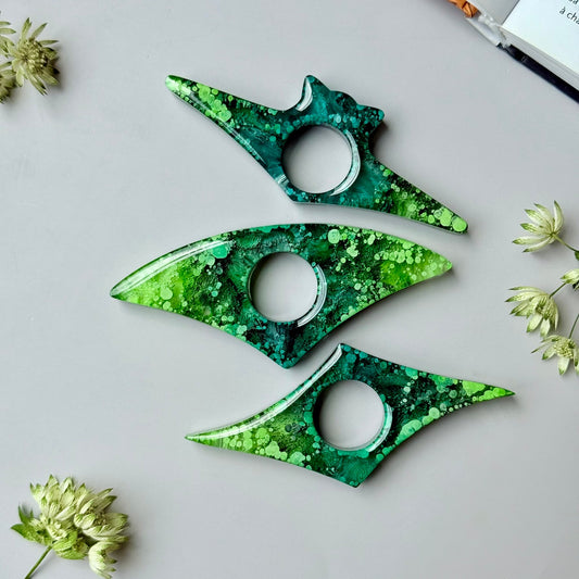Handmade resin page holders with green and teal petri effect, displayed flat on a neutral background with dried flowers.