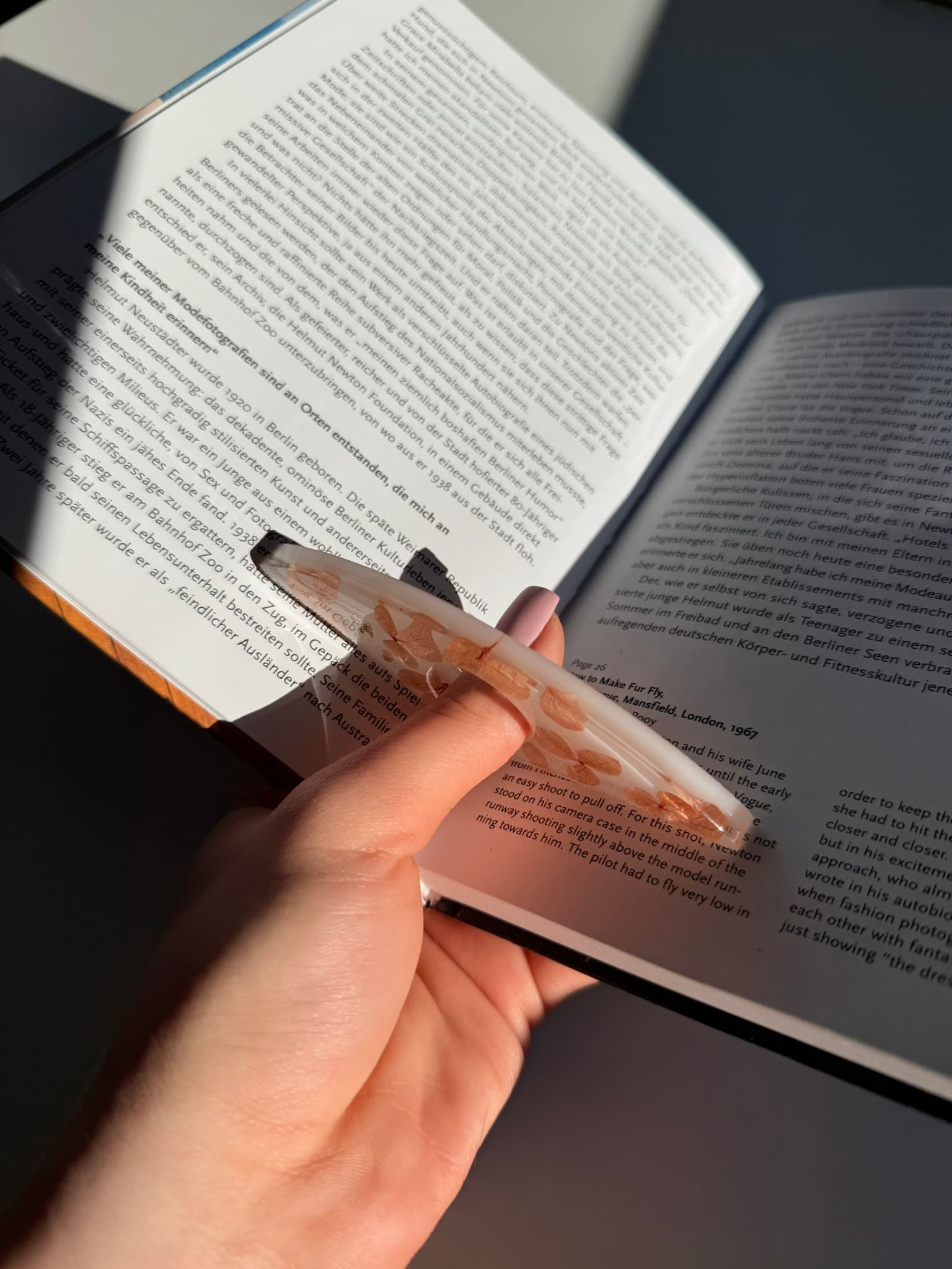 Hand holding handmade page holder over an open book