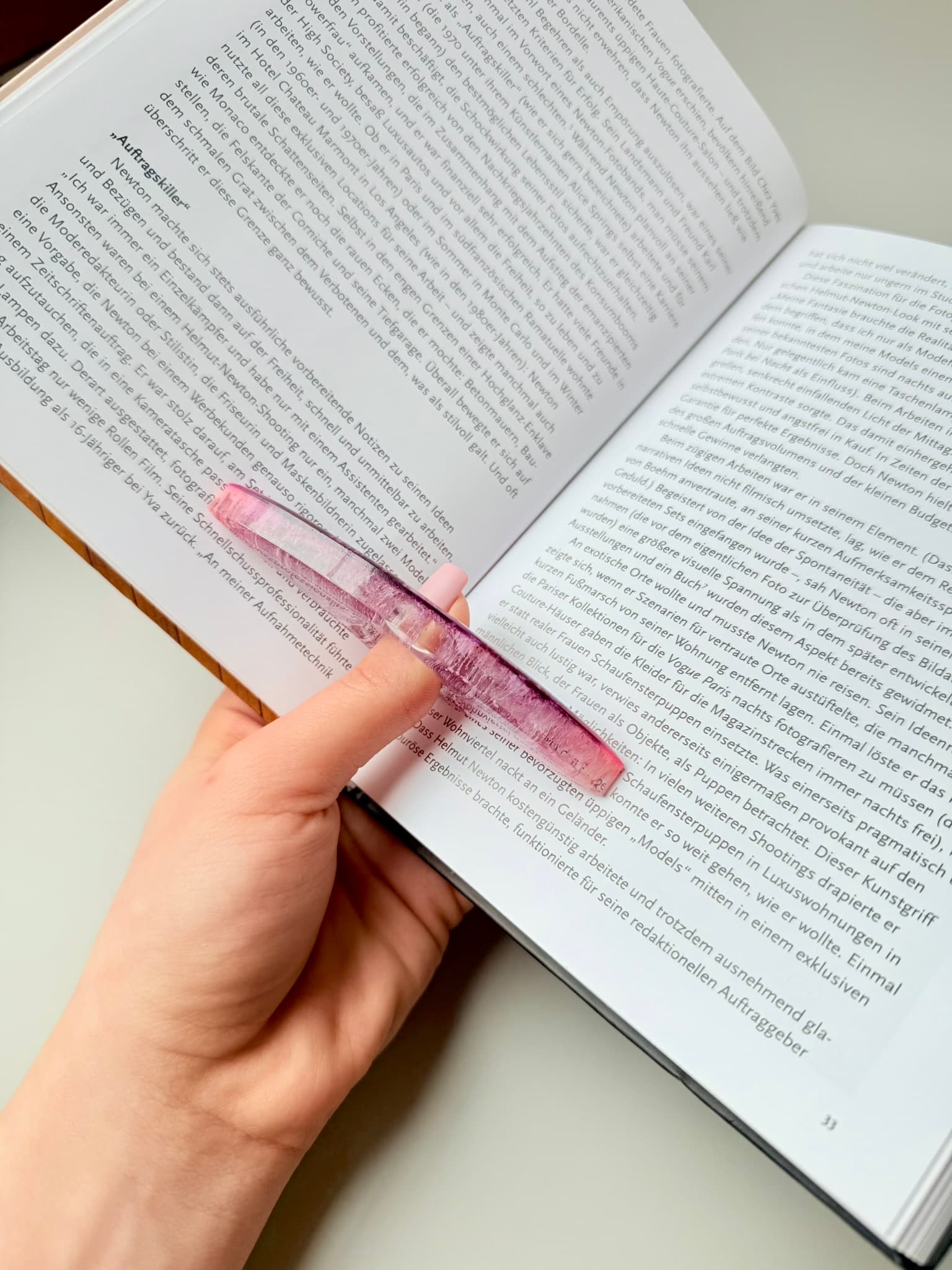 Hand holding a pink handmade page holder over an open book