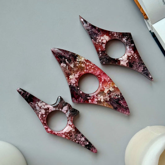 Handmade resin page holders in red, pink, and black petri design, styled flat with abstract shapes and a neutral background.