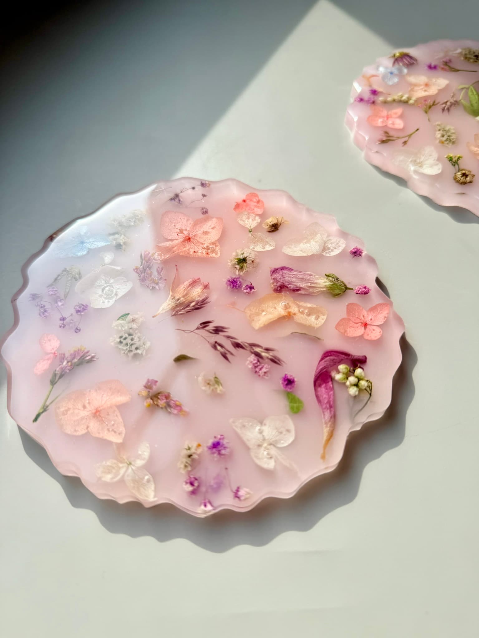 Handmade pink coasters with floral elements on a light background